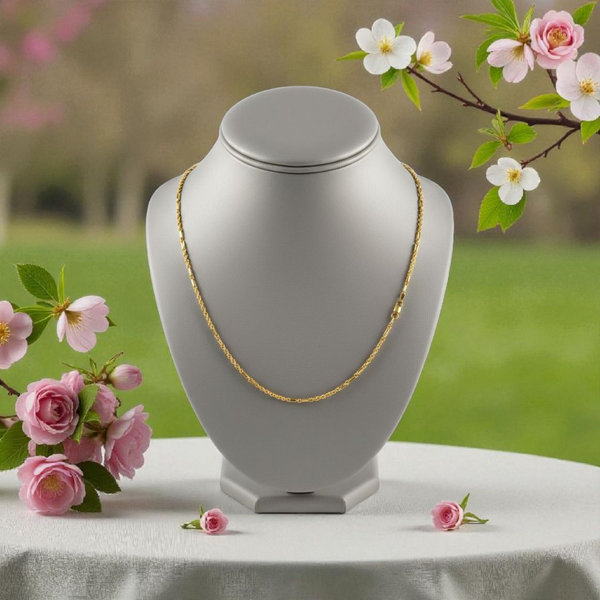 Gray necklace display with gold chain and pink flowers in the background